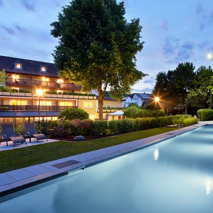 Garden & Spa Hotel das Götzfried © Michael Huber Fotographie Beleuchteter Außenpool und Gartenbereich eines Hotels bei Dämmerung