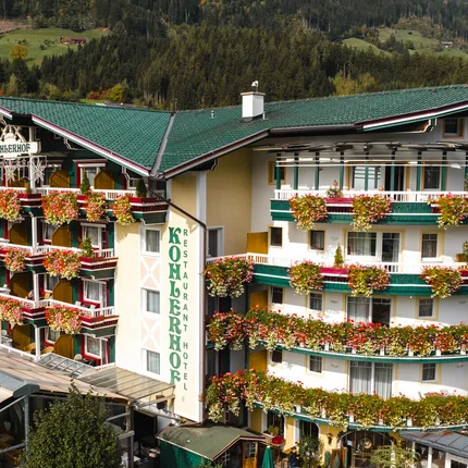 Hotel Kohlerhof © Jukkapehkonen Photography Hotel mit grünen Dächern und bunten Blumen an Balkonen in den Bergen