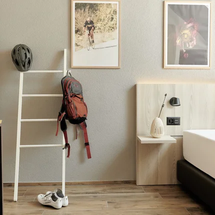 Natur- und Bikehotel Balga © Paolo Vaccariello Hotelzimmer mit Fahrradzubehör neben einem Bett und dekorativen Bildern