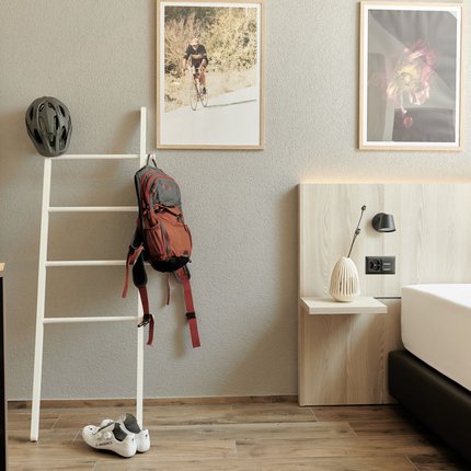 Natur- und Bikehotel Balga © Paolo Vaccariello Hotelzimmer mit Fahrradzubehör neben einem Bett und dekorativen Bildern