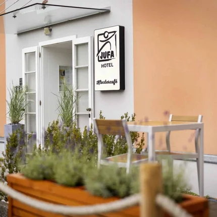 JUFA Hotel Judenburg © JUFA Hotels - Harald Eisenberger Eingang des JUFA Hotels mit Außentisch und Pflanzen