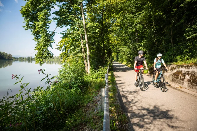 Velontour © Velontour Zwei Radfahrer auf einem Weg neben einem Fluss im Wald