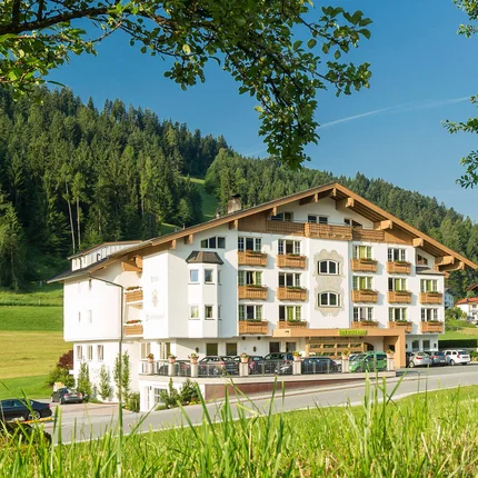 Hotel Thierseerhof © Hotel Thierseerhof GmbH Hotelgebäude in grüner Landschaft mit Bäumen und Bergen im Hintergrund