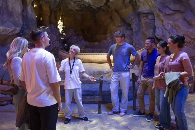 Velontour © Bavaria Filmstadt Eine Gruppe hört einem Guide in einer beleuchteten Höhle zu
