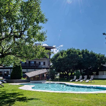 Hotel ANDER © Auer Lukas Photography Sonniger Garten mit Pool und Liegestühlen unter Bäumen