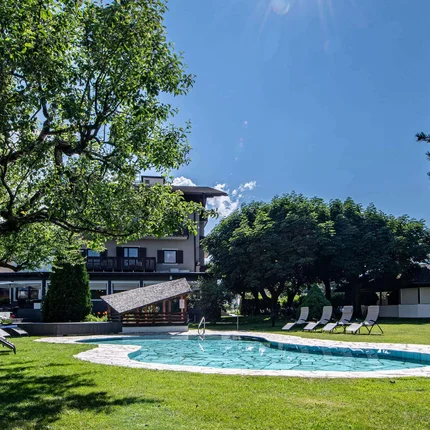 Hotel ANDER © Auer Lukas Photography Sonniger Garten mit Pool und Liegestühlen unter Bäumen