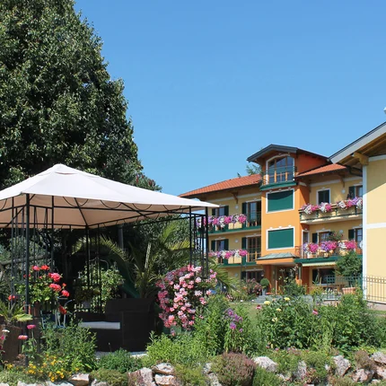 Ferienhotel Herzog © Ferienhotel Herzog Garten mit Pavillon und bunten Blumen vor buntem Wohnhaus