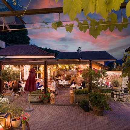 Hotel Gasthaus Blaue Quelle © Blaue Quelle in Erl - Dabernig Abendessen auf der beleuchteten Terrasse eines Restaurants mit Gästen