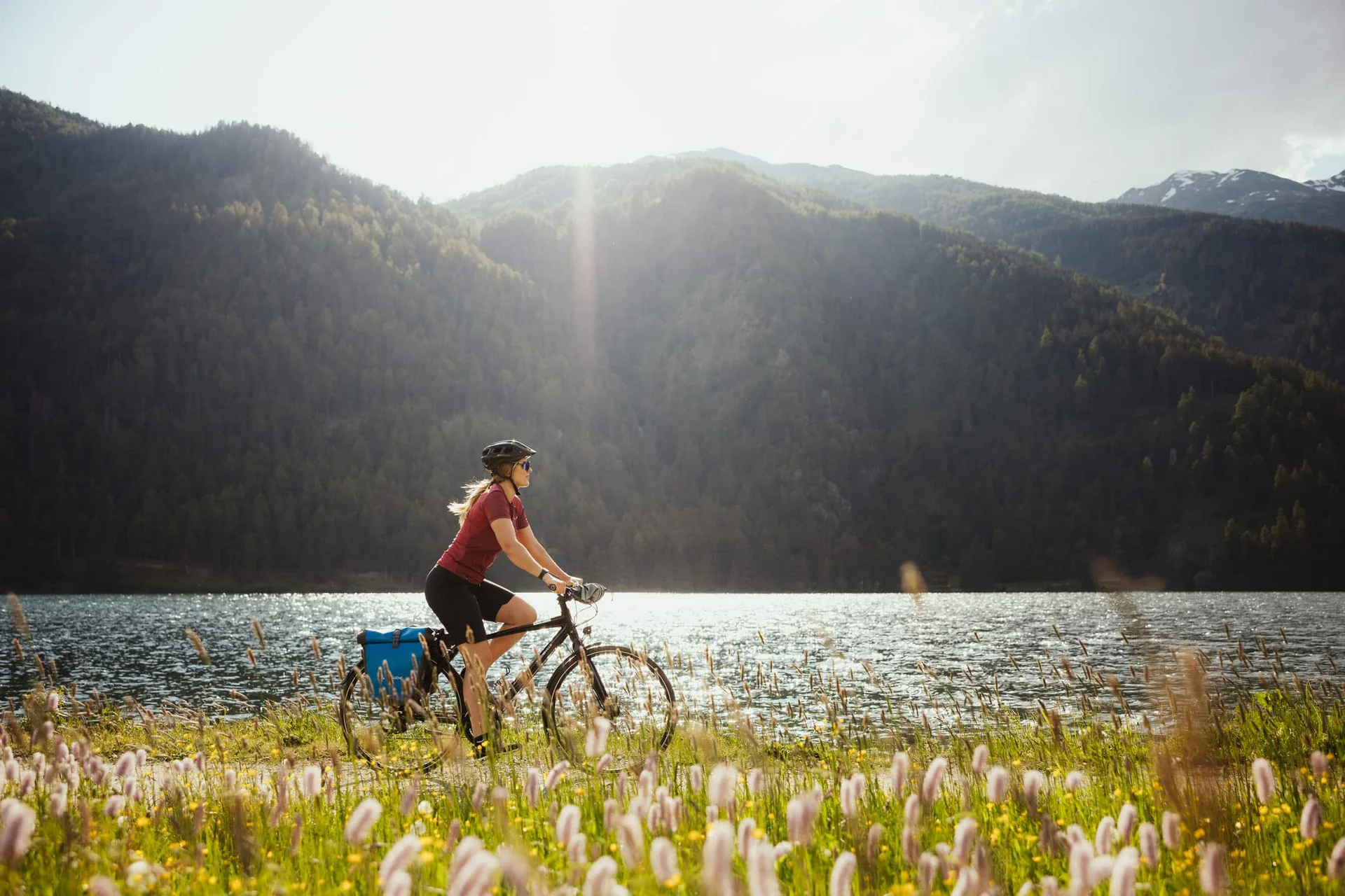 Velontour © IDM Südtirol - Alex Moling Frau fährt Fahrrad am Seeufer mit Bergen im Hintergrund