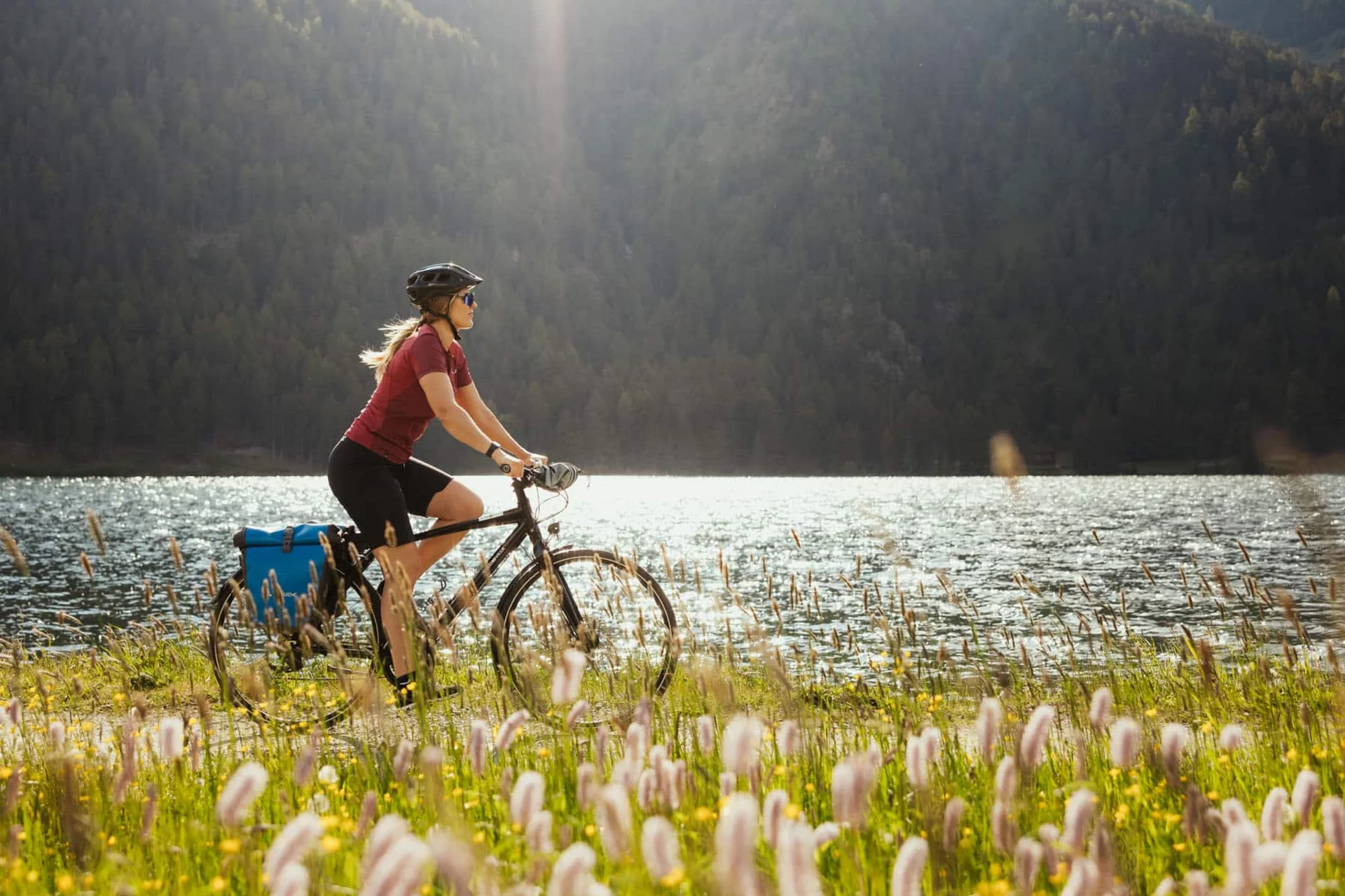 Velontour © IDM Südtirol - Alex Moling Frau fährt Fahrrad am Seeufer mit Bergen im Hintergrund