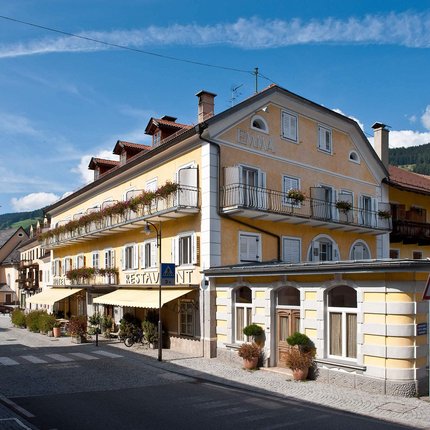 Emma Historic Hotel © Foto Klick Gelbes Hotel mit Balkonblumen im sonnigen Dorf mit Kirche und Bergen