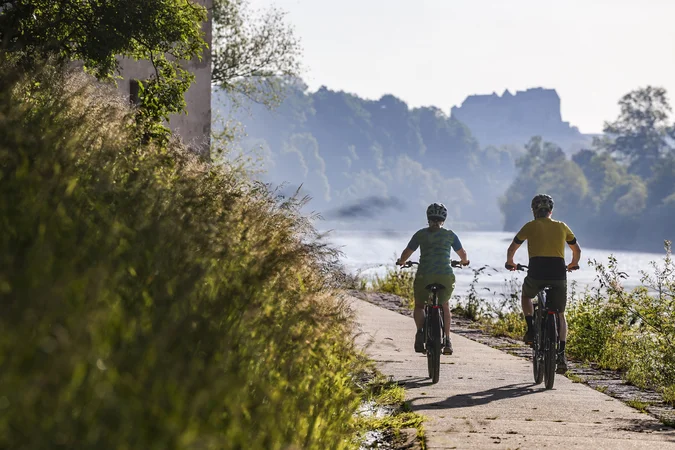 Velontour © Velontour - Heiko Mandl Zwei Radfahrer auf einem Flussweg bei sonnigem Wetter