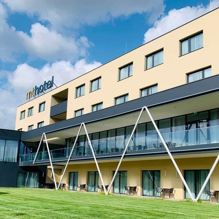 MT Hotel © MT Hotel GmbH in Zeltweg Modernes Hotelgebäude mit grüner Rasenfläche und blauem Himmel