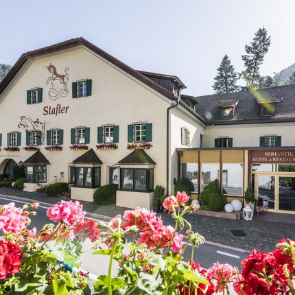 Romantik Hotel Stafler © Hannes Niederkofler Hotel und Restaurant Stafler in den Bergen mit Blumen im Vordergrund