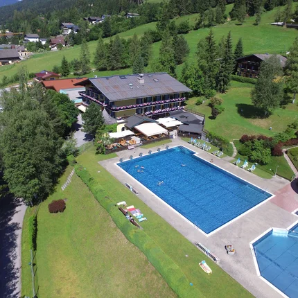 Sporthotel Radstadt © Lakenmacher Hotel GmbH - Christian Postl Außenpool mit Wasserrutsche neben einem Hotel in grüner Berglandschaft
