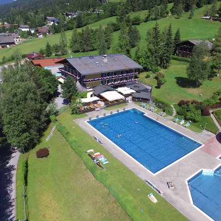 Sporthotel Radstadt © Lakenmacher Hotel GmbH - Christian Postl Außenpool mit Wasserrutsche neben einem Hotel in grüner Berglandschaft