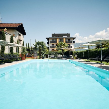 Hotel Traminerhof © Manuel Ferrigato Blick auf einen Außenpool mit Liegestühlen und Sonnenschirmen vor einem Gebäude