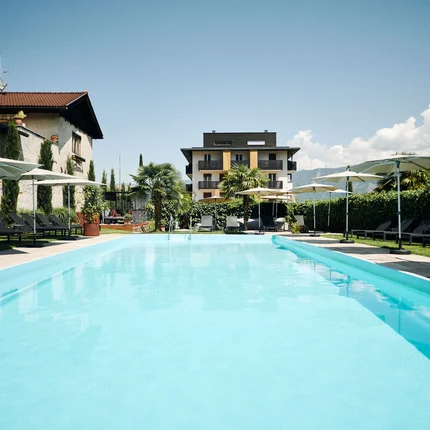 Hotel Traminerhof © Manuel Ferrigato Blick auf einen Außenpool mit Liegestühlen und Sonnenschirmen vor einem Gebäude
