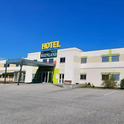 Hotel Weinland © Hotel Weinland Donnerskirchen Außenansicht des Hotels Weinland mit Parkplatz und blauem Himmel