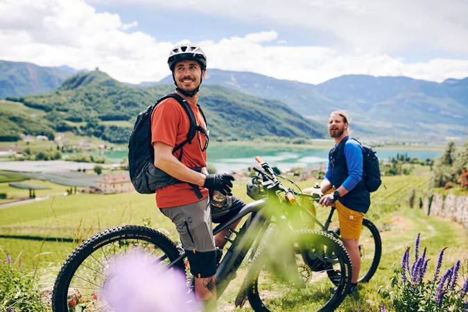 Velontour © IDM Südtirol - Manuel Ferrigato Zwei Radfahrer in den Bergen mit Blick auf See und Tal