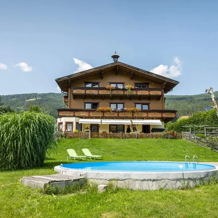 Landhaus Aubauerngut © Lorenz Masser Fotografie Haus mit Balkon, Garten, Pool und Liegestühlen vor bewaldetem Berg